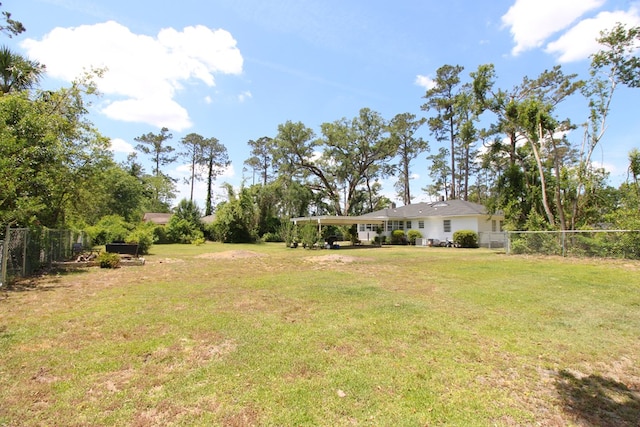 view of yard featuring fence and a carport