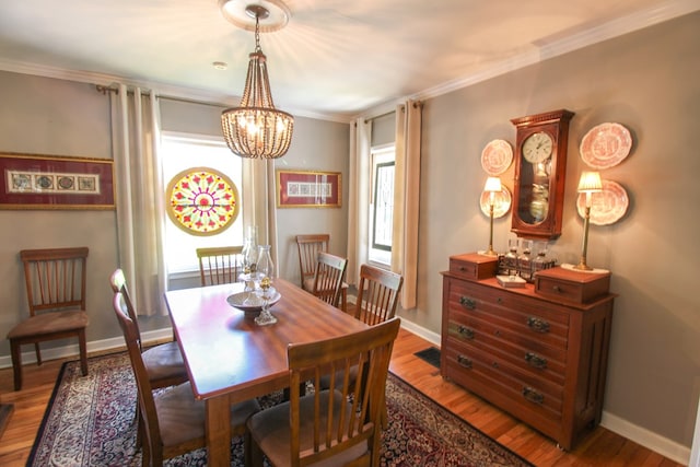 dining area featuring baseboards, ornamental molding, wood finished floors, and a chandelier