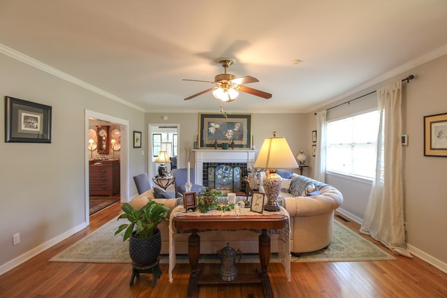 living room with crown molding, a fireplace, wood finished floors, and a wealth of natural light