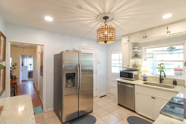 kitchen with light tile patterned flooring, light stone countertops, appliances with stainless steel finishes, a sink, and white cabinetry
