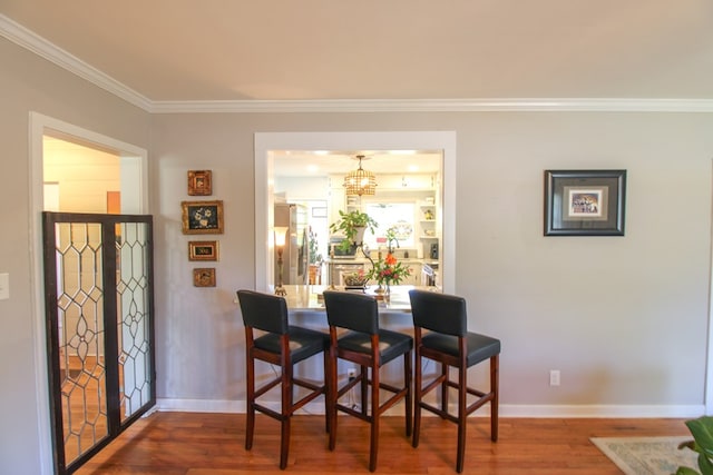 dining space featuring baseboards, ornamental molding, wood finished floors, and a notable chandelier