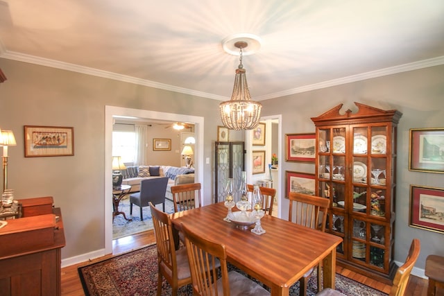 dining room with baseboards, ornamental molding, wood finished floors, and a chandelier