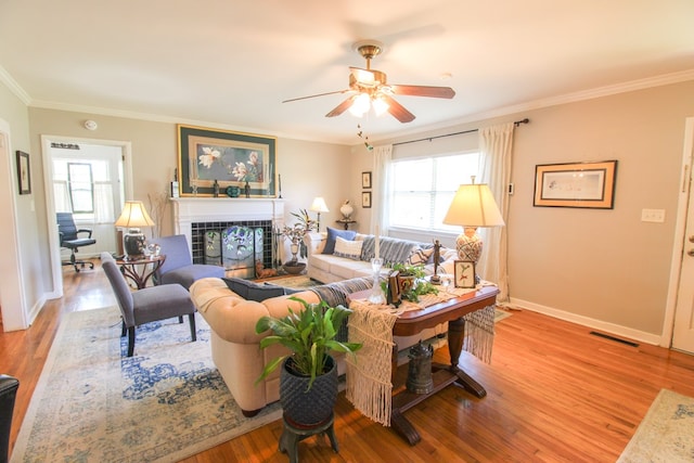 living room with visible vents, a healthy amount of sunlight, a fireplace, baseboards, and light wood-style floors