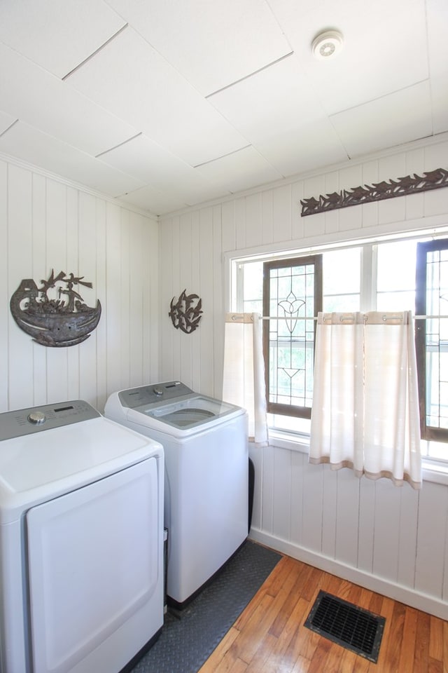 laundry area featuring laundry area, washing machine and dryer, wood finished floors, and visible vents