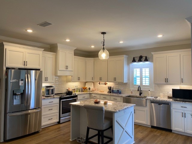 kitchen featuring white cabinetry, stainless steel appliances, a center island, and sink