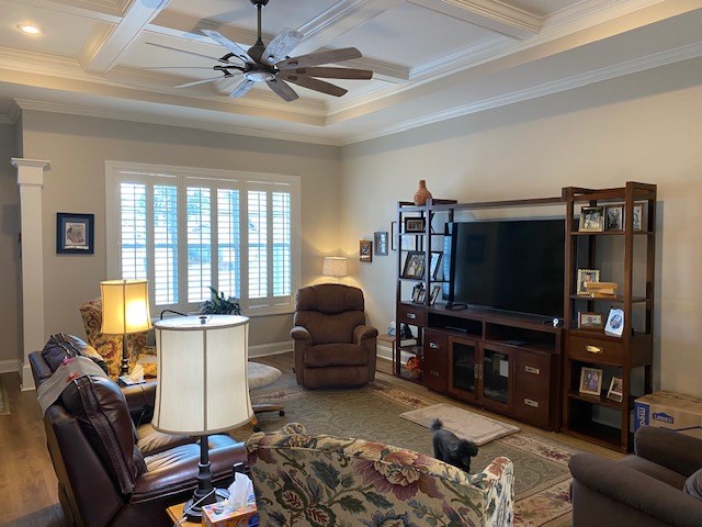 living room featuring ceiling fan, ornamental molding, coffered ceiling, and beam ceiling