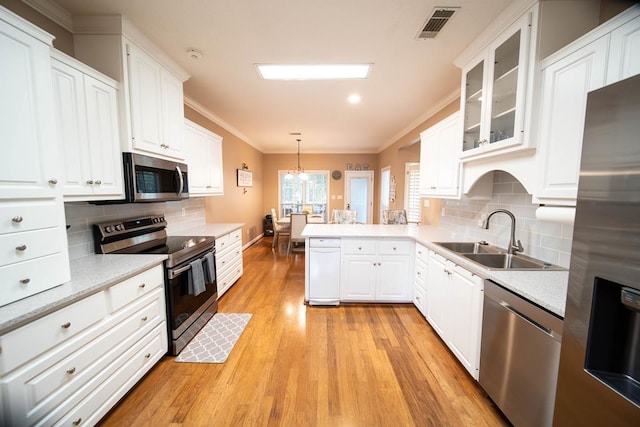 kitchen featuring sink, light wood-type flooring, hanging light fixtures, and appliances with stainless steel finishes