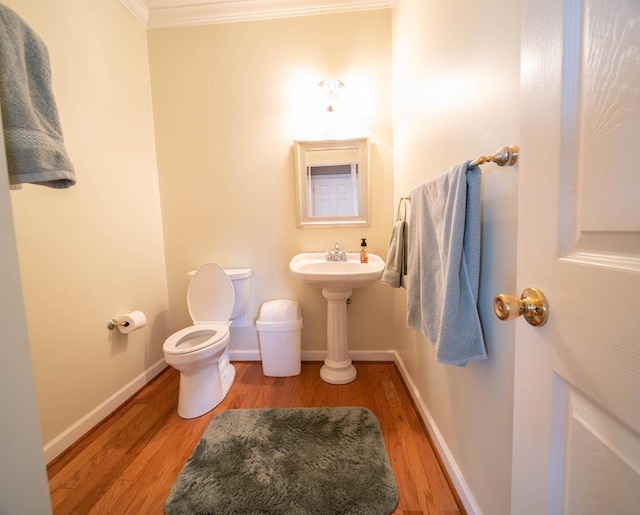 bathroom with hardwood / wood-style flooring, toilet, and crown molding