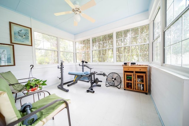 workout room featuring ceiling fan and wooden walls