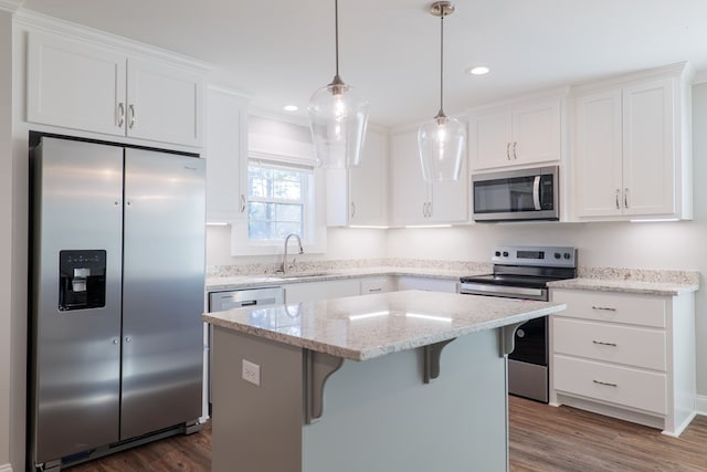 kitchen featuring stainless steel appliances, white cabinets, a kitchen island, and sink