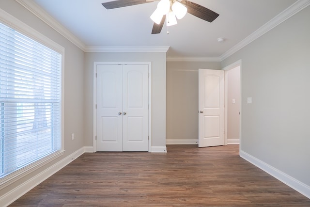 unfurnished bedroom with ceiling fan, dark hardwood / wood-style flooring, crown molding, and a closet