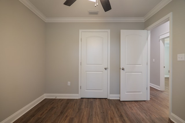 unfurnished bedroom with ceiling fan, dark wood-type flooring, and crown molding