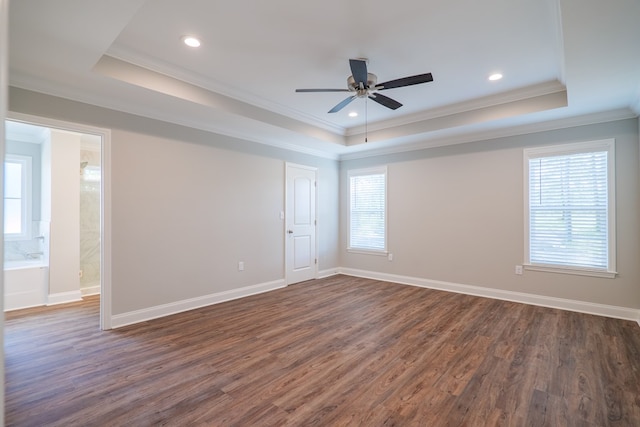 spare room with dark wood-type flooring, crown molding, a tray ceiling, and ceiling fan