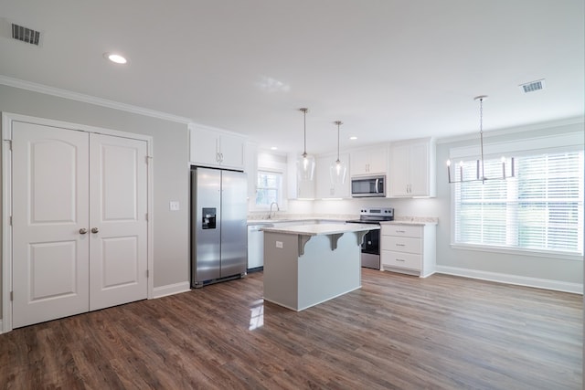 kitchen featuring white cabinetry, pendant lighting, appliances with stainless steel finishes, and a kitchen island