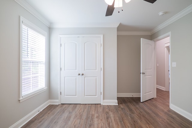 unfurnished bedroom with ceiling fan, a closet, crown molding, and multiple windows