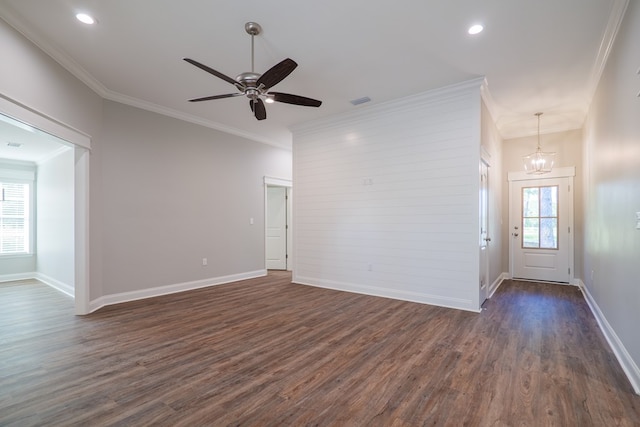 empty room with ceiling fan with notable chandelier, dark hardwood / wood-style floors, and ornamental molding