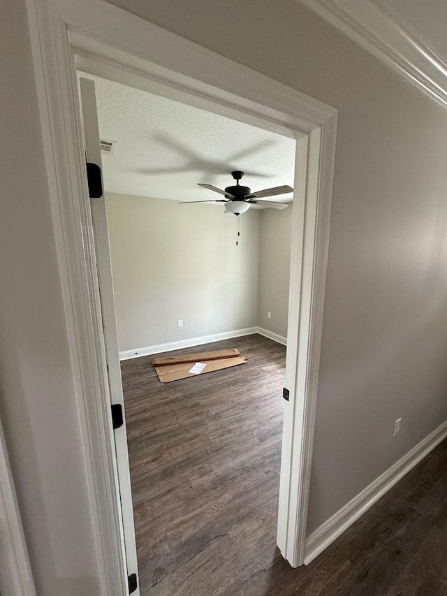 empty room with a textured ceiling, dark hardwood / wood-style floors, and ceiling fan