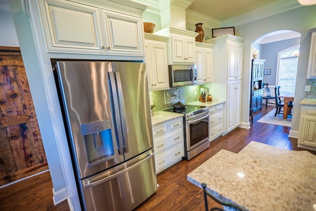 5643 Timberwind Cir, Lake Park, GA 31636 - kitchen featuring stainless steel appliances, arched walkways, tasteful backsplash, light stone countertops, and dark wood finished floors