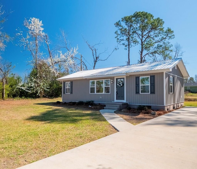 view of front of home with metal roof and a front lawn