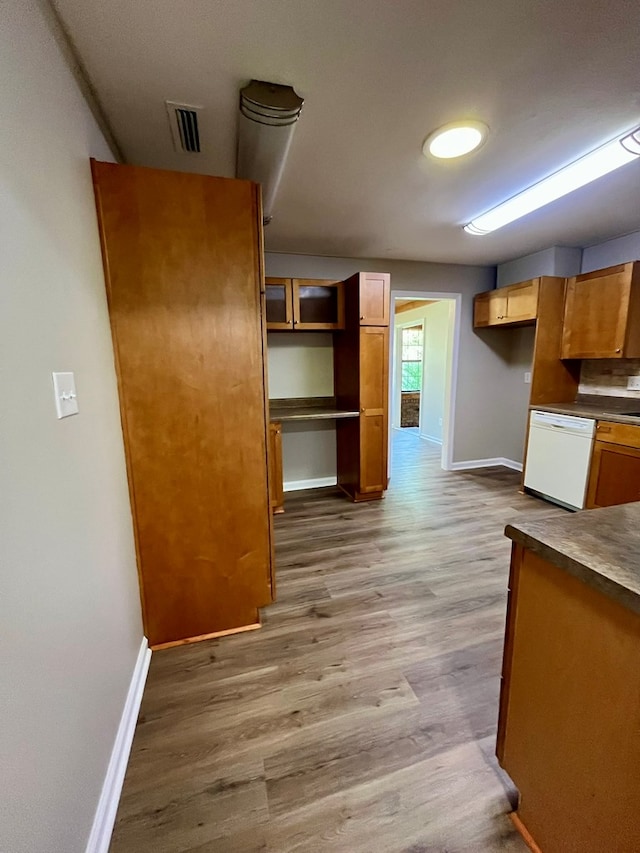 kitchen featuring visible vents, dishwasher, light wood-style flooring, baseboards, and dark countertops