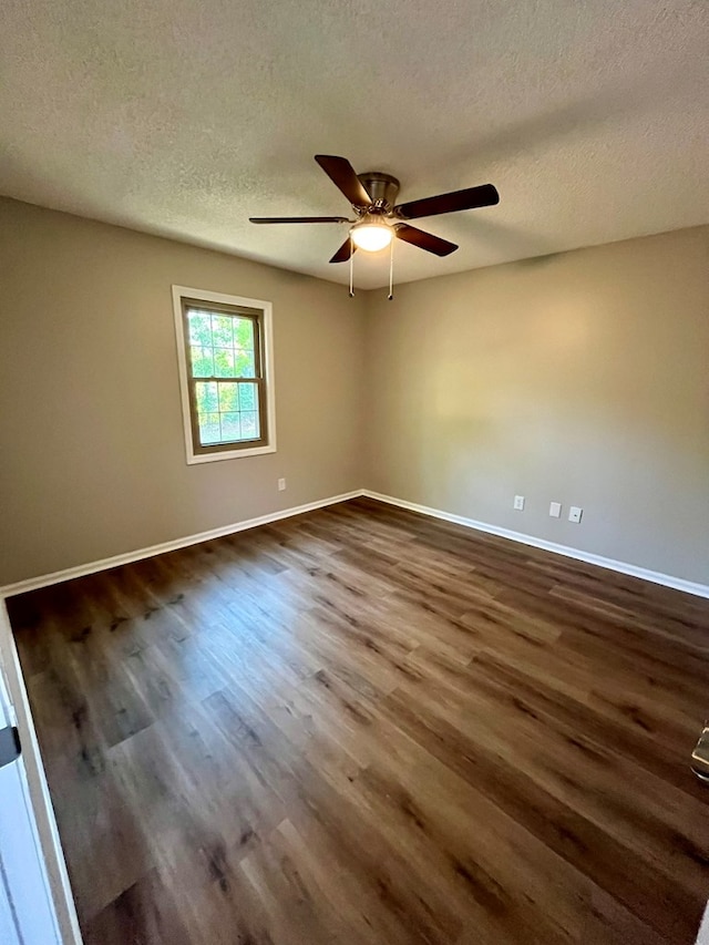 unfurnished room featuring baseboards, ceiling fan, a textured ceiling, and dark wood-type flooring