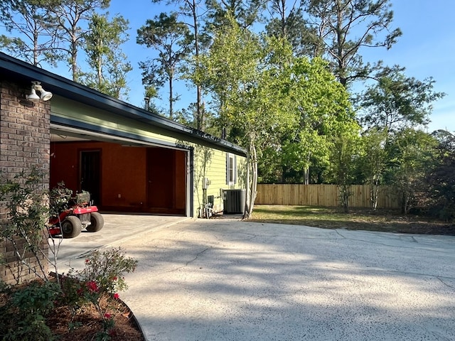 view of property exterior featuring fence, central AC, and driveway