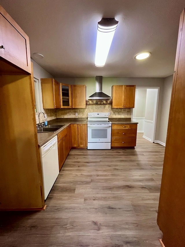 kitchen featuring a sink, tasteful backsplash, white appliances, wall chimney exhaust hood, and dark countertops