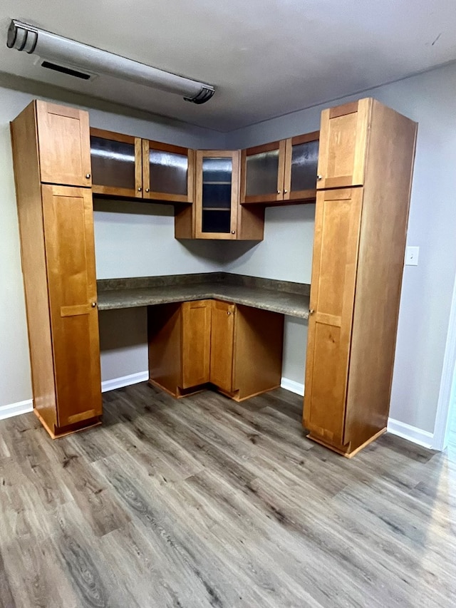 interior space featuring built in study area, visible vents, wood finished floors, and baseboards