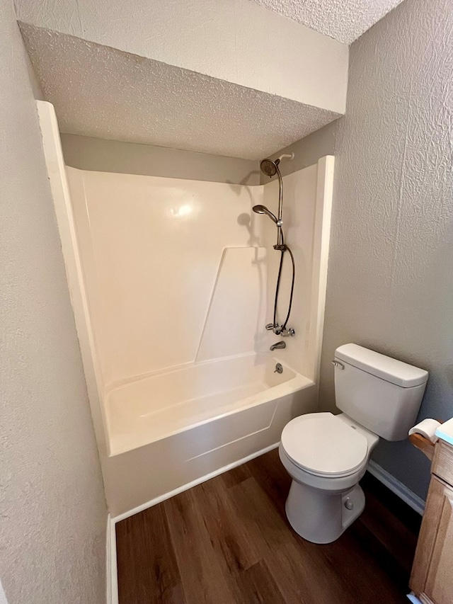 full bath featuring a textured ceiling, bathing tub / shower combination, wood finished floors, and toilet