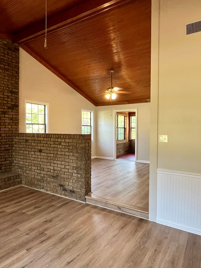 spare room with a ceiling fan, visible vents, wood ceiling, wood finished floors, and lofted ceiling with beams