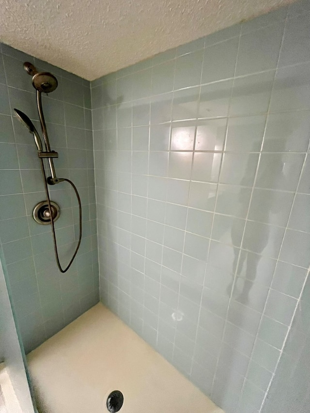 bathroom featuring a textured ceiling and tiled shower