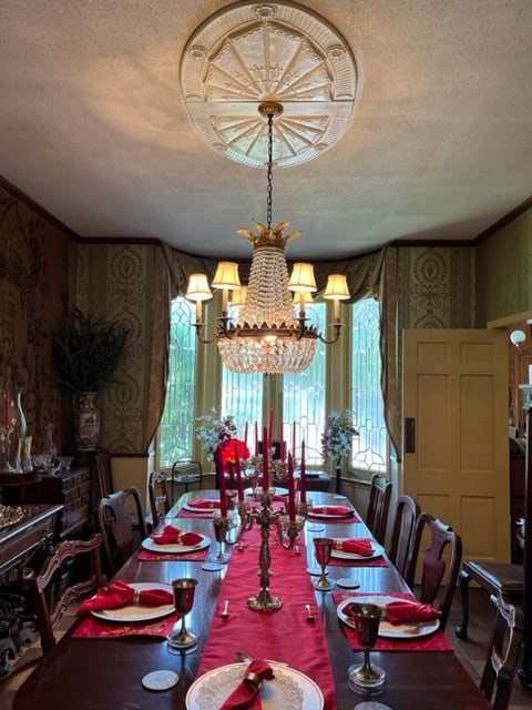 dining room featuring ornamental molding, a notable chandelier, and a textured ceiling