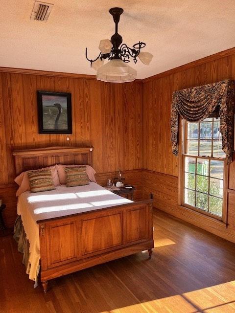 bedroom featuring hardwood / wood-style flooring, a textured ceiling, and wood walls