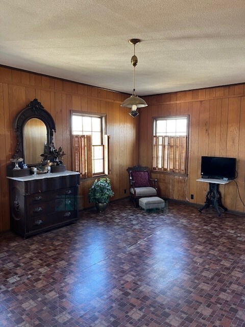 sitting room featuring a textured ceiling and wood walls