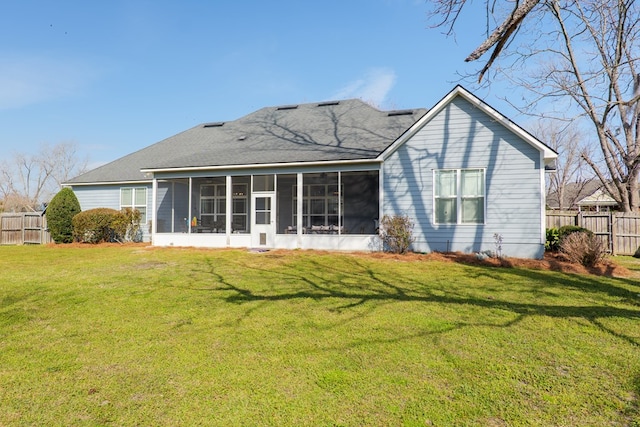 rear view of property with a sunroom, fence, and a yard