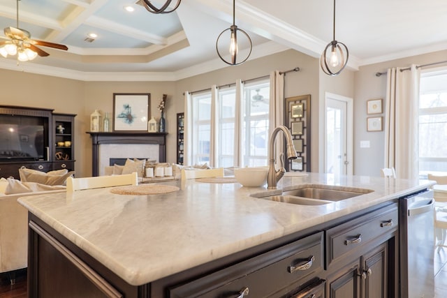 kitchen featuring coffered ceiling, a sink, open floor plan, ornamental molding, and a center island with sink