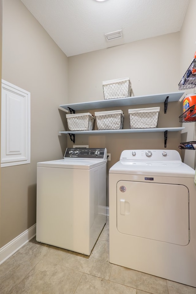 laundry area featuring baseboards, laundry area, light tile patterned floors, and washer and dryer