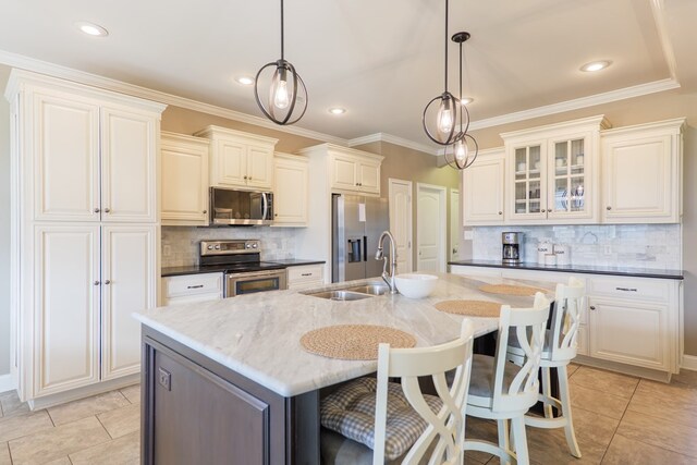 kitchen with stainless steel appliances, a sink, an island with sink, and light tile patterned floors