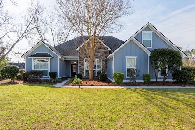 view of front of house with stone siding, a front lawn, board and batten siding, and roof with shingles