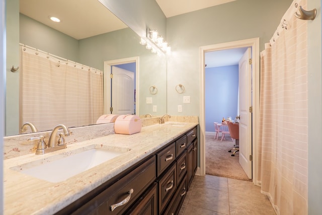 full bath with baseboards, double vanity, a sink, and tile patterned floors