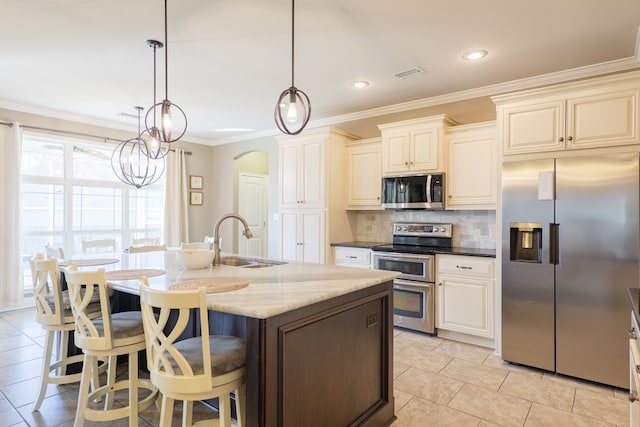 kitchen featuring arched walkways, tasteful backsplash, visible vents, appliances with stainless steel finishes, and a sink