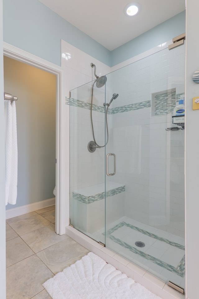 full bath with a stall shower, tile patterned flooring, and toilet