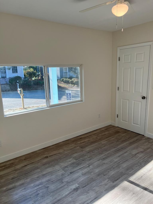 empty room with ceiling fan, dark hardwood / wood-style floors, and a wealth of natural light