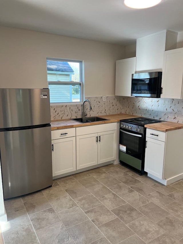 kitchen featuring stainless steel appliances, sink, white cabinets, and wood counters