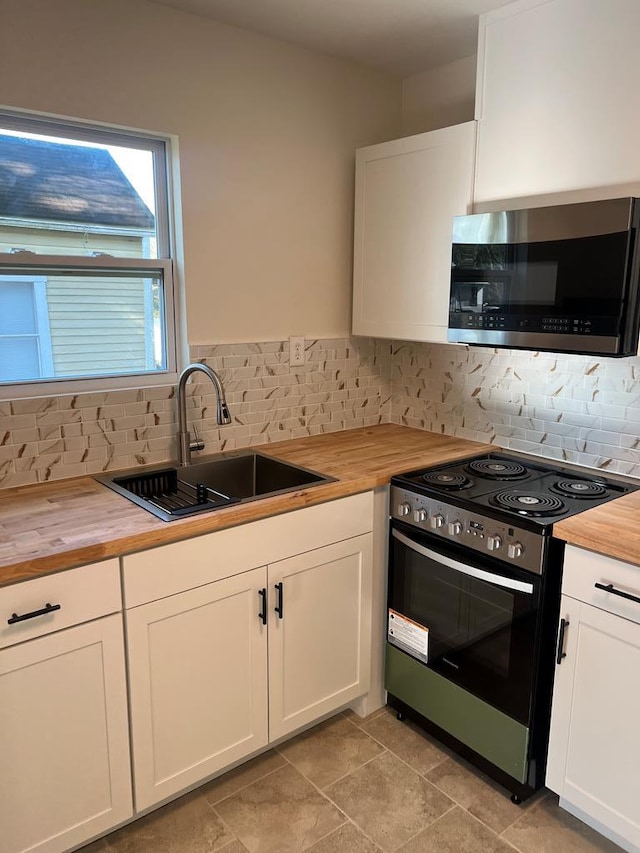 kitchen featuring white cabinetry, wood counters, stainless steel appliances, and sink