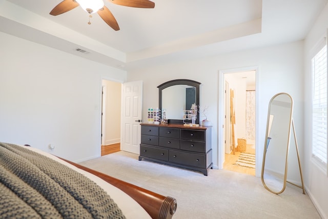 carpeted bedroom featuring a raised ceiling, visible vents, multiple windows, and baseboards