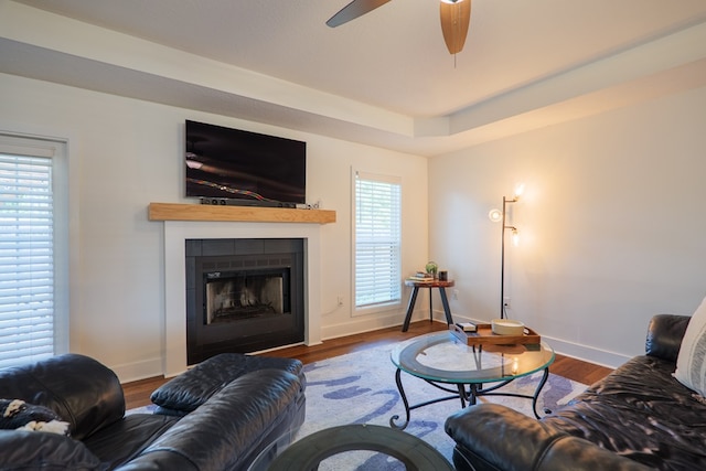 living room with wood finished floors, a ceiling fan, and a fireplace