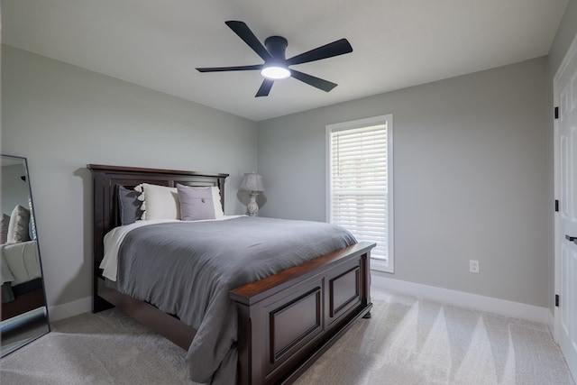bedroom with light colored carpet, a ceiling fan, and baseboards