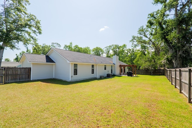 rear view of property with a chimney, a yard, central AC, and a fenced backyard