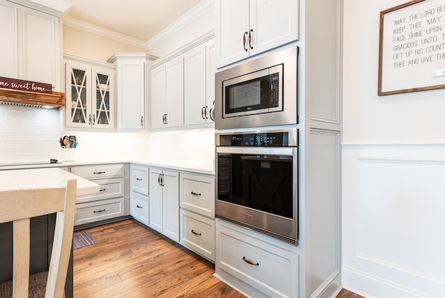 3041 Houser Way, Hahira, GA 31632 - kitchen with appliances with stainless steel finishes, light countertops, crown molding, and light wood-style floors